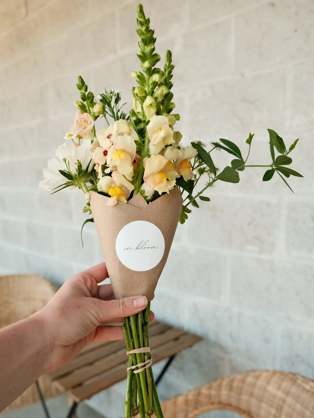 A wrapped bouquet of snapdragons and cosmos