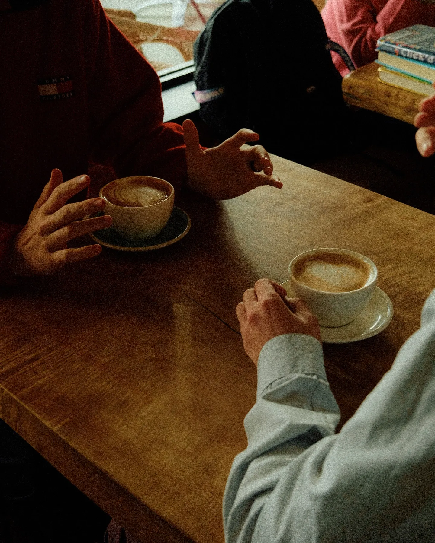 Friends chatting over coffee at a wooden table at Cafe Amarti